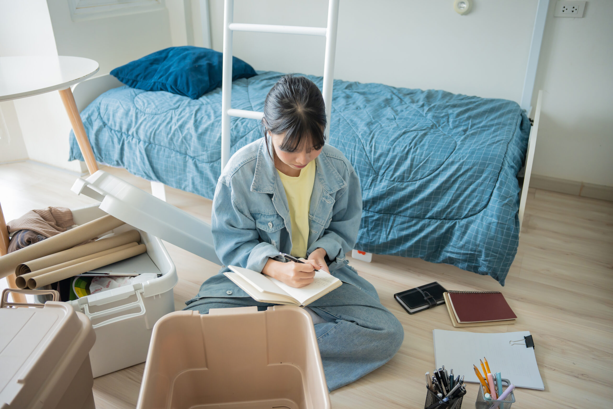 A girl packing on the floor for college.