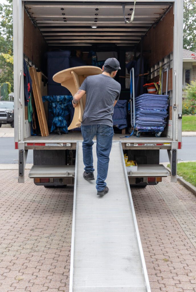 A professional mover carrying a table into a truck.