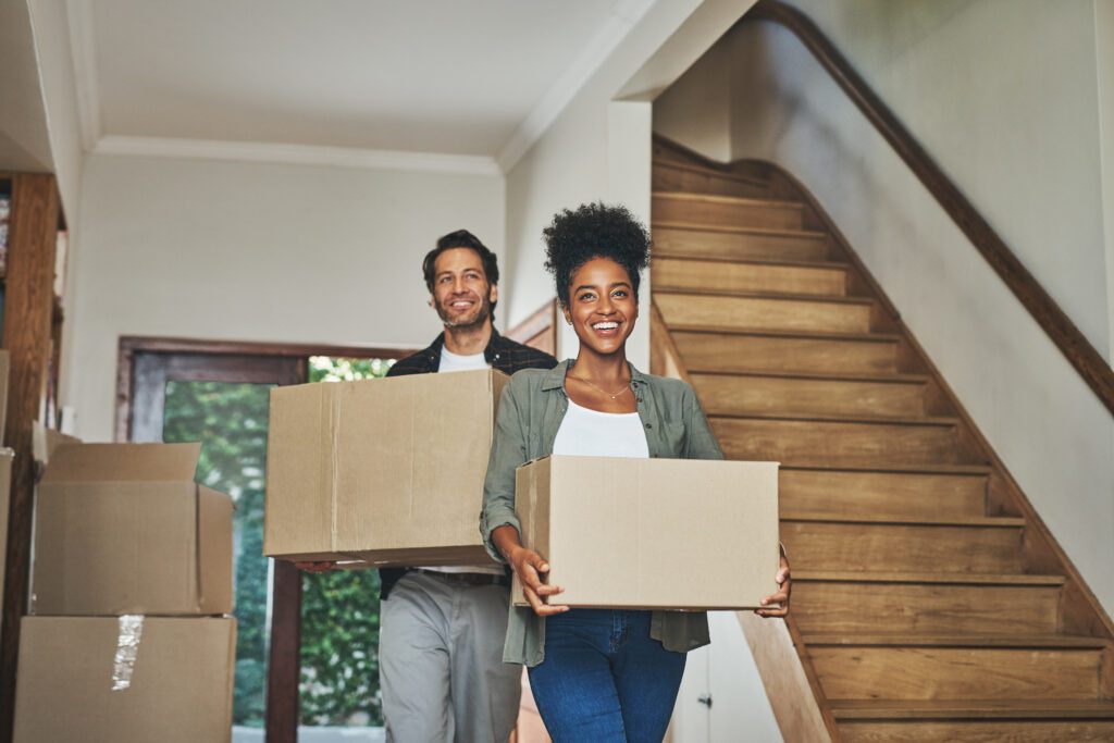 Two people moving boxes in their new home.