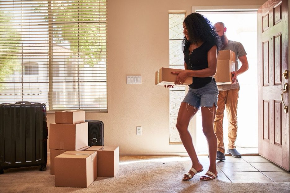 A couple arriving at their new home with boxes.