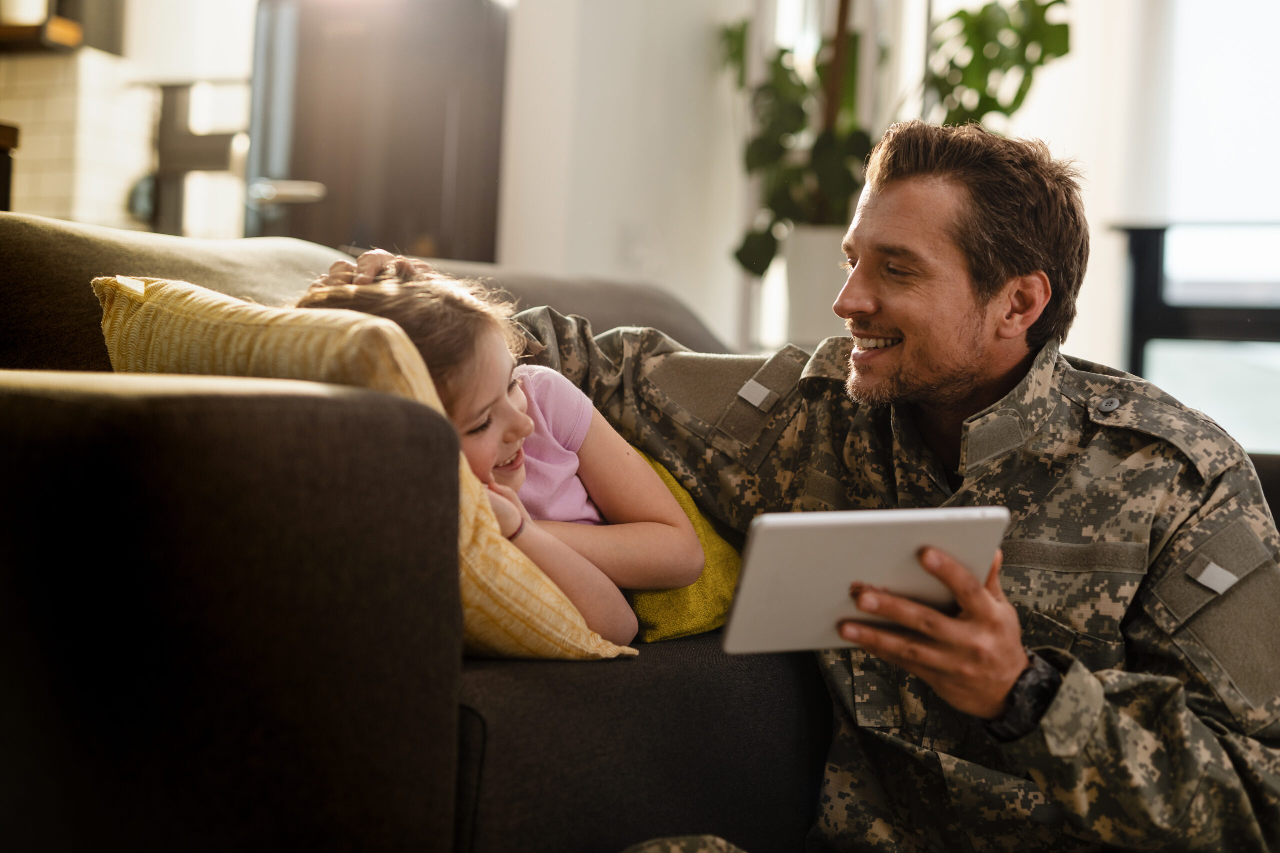 Happy soldier and his small daughter using touchpad at home.