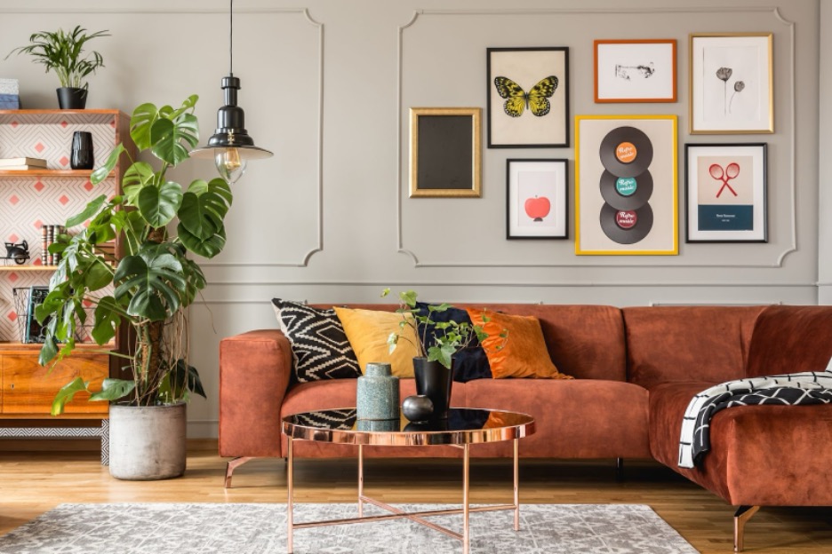 A variety of art hanging on a wall over a couch.