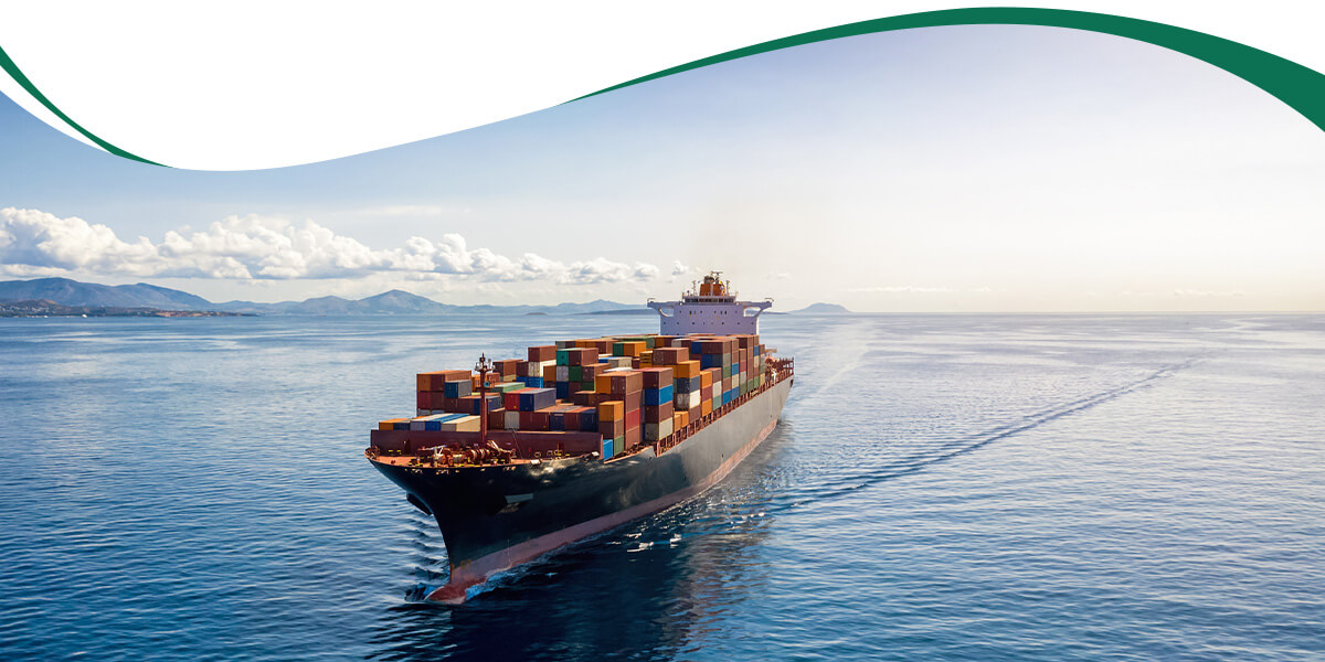 Container ship sailing on calm blue sea with stacked colorful cargo containers on deck, horizon in the distance of mountains and clouds.